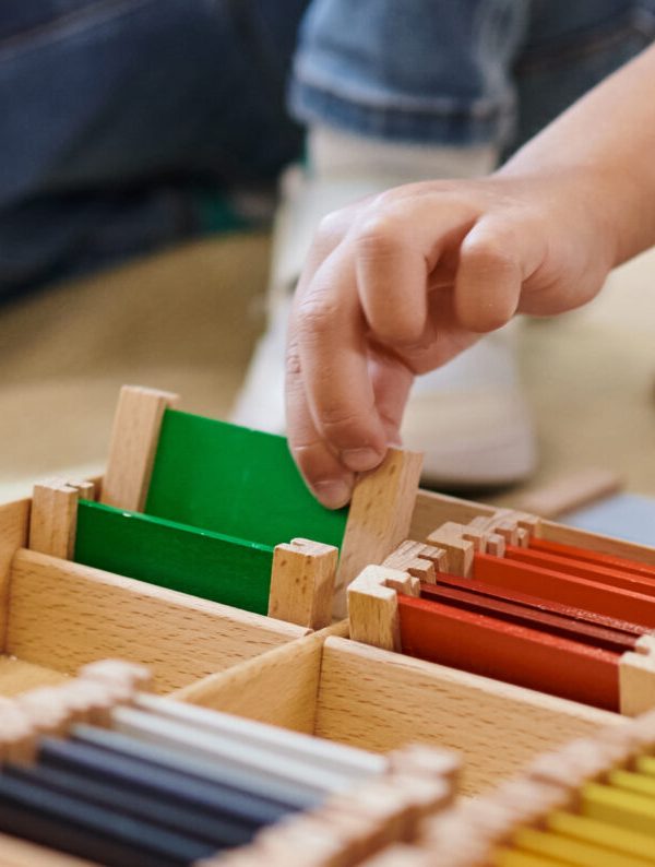 montessori school concept, cropped view of girl playing color matching game near teacher, banner